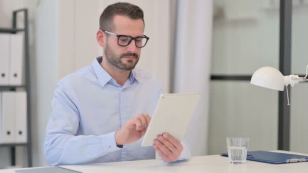 Mann mittleren Alters nutzt Tablet bei der Arbeit — Stockvideo