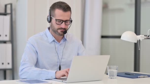 Moyen Age Homme avec casque regardant la caméra tout en utilisant un ordinateur portable — Video