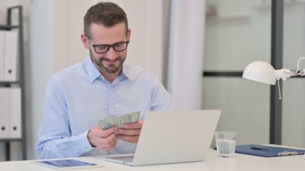 Homem de meia-idade contando dólares enquanto trabalhava no laptop — Vídeo de Stock