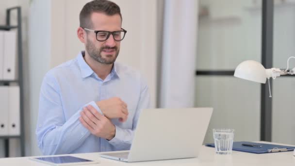 Mann mittleren Alters hat Handgelenkschmerzen bei der Arbeit am Laptop — Stockvideo