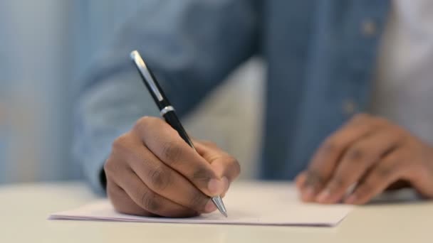 Mãos do homem africano escrevendo sobre papel com caneta, close-up — Vídeo de Stock