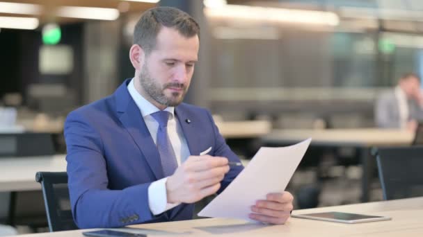 Geschäftsmann mittleren Alters liest Dokumente im Büro — Stockvideo