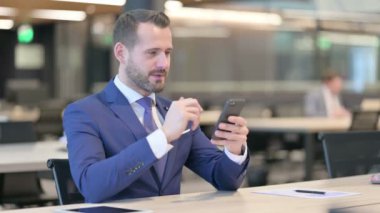 Orta Yaşlı İşadamı İşyerinde Akıllı Telefondan Başarı Kutlaması 