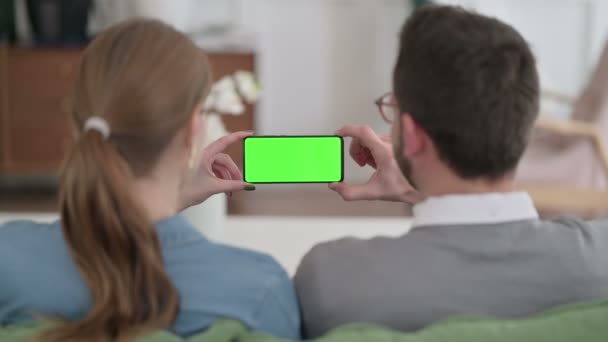 Vista trasera de la pareja sosteniendo Smartphone con pantalla de clave de croma verde — Vídeos de Stock