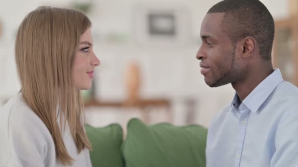 Feliz pareja de raza mixta sonriéndose cariñosamente en casa — Vídeos de Stock