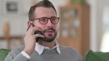 Orta yaşlı adam evde akıllı telefondan konuşuyor. 