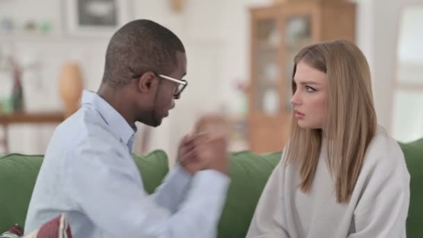 Africký muž bojuje s kavkazskou ženou, zatímco sedí na pohovce — Stock video