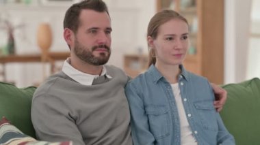 Kanepede otururken kameraya bakan Ciddi Çift 