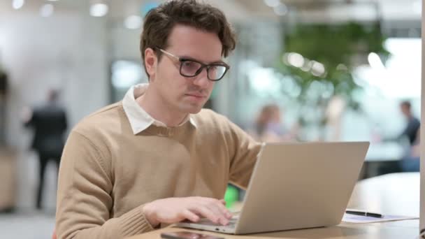 Diseñador masculino joven con el ordenador portátil que muestra pulgares hacia abajo — Vídeos de Stock