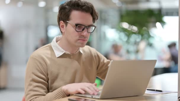Diseñador masculino joven con ordenador portátil mirando a la cámara — Vídeos de Stock