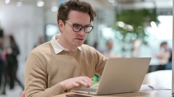 Diseñador masculino joven con tos en el ordenador portátil en la oficina — Vídeos de Stock