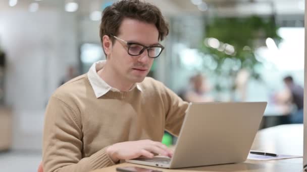 Diseñador masculino joven con la sonrisa del ordenador portátil en la cámara — Vídeos de Stock