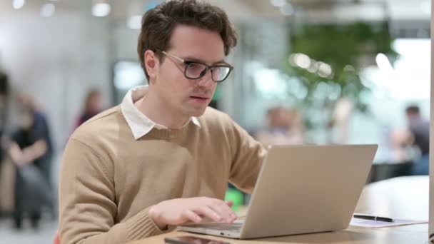 Diseñador masculino joven que tiene pérdida en el ordenador portátil en la oficina — Vídeos de Stock