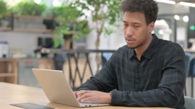 Dizüstü bilgisayarı olan Afrikalı Amerikalı adamın sırt ağrısı var. 