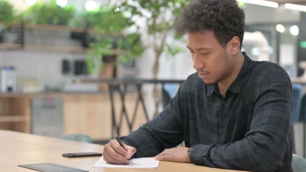 Pensativo hombre afroamericano escribiendo en papel — Vídeos de Stock