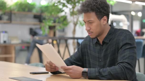 Hombre afroamericano teniendo pérdida mientras lee documentos — Vídeos de Stock