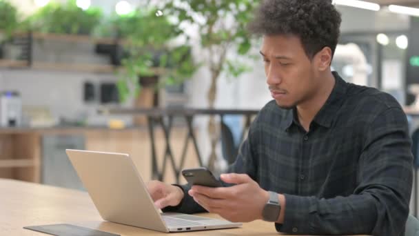 African American Man with Laptop menggunakan Smartphone di Kantor — Stok Video