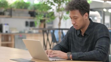 Dizüstü bilgisayarı olan Afrikalı Amerikalı adamın boynu ağrıyor. 