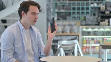 Genç adam Kafe 'de Smartphone' da konuşuyor. 