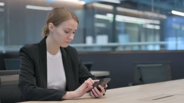 İş yerinde akıllı telefon kullanan çekici bir iş kadını. 