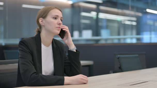 Wütende Geschäftsfrau spricht am Arbeitsplatz über Smartphone — Stockvideo