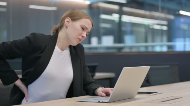 Безробітна жінка, яка відчуває біль у спині, користуючись ноутбуком — стокове відео