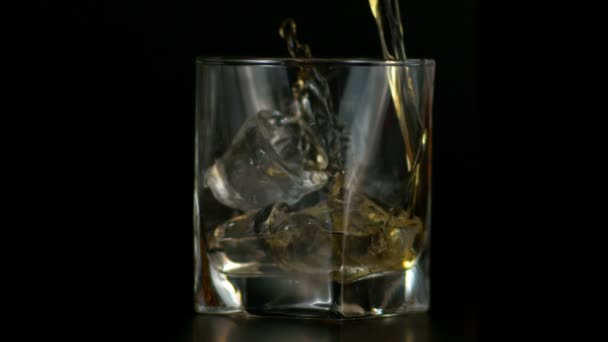 Langzame beweging van het gieten van Whiskey in glas met ijs, donkere achtergrond — Stockvideo