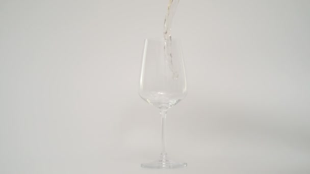 Moción lenta de verter vino blanco en vidrio inclinado, fondo blanco — Vídeo de stock