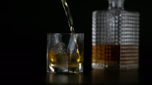 Super Slow Motion of Pouring Alcohol σε ποτήρι με μπουκάλι ουίσκι στο παρασκήνιο — Αρχείο Βίντεο