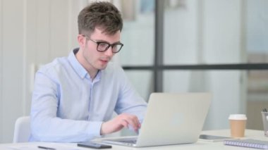 Laptoplu genç adam öksürüyor. 