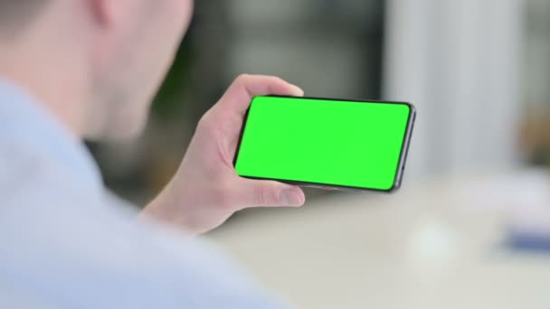 Achteraanzicht van de jonge man op zoek naar Smartphone met Chroma Screen — Stockvideo