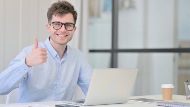 Dizüstü bilgisayarlı Genç Adam Başparmağını kaldırdı 