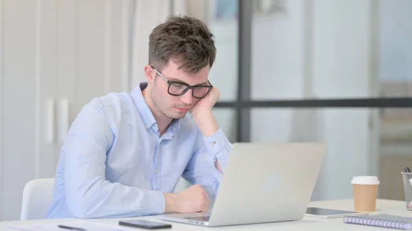 Jeune homme avec ordinateur portable faisant la sieste au bureau — Photo