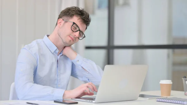 Młody człowiek z laptopem ma ból szyi — Zdjęcie stockowe