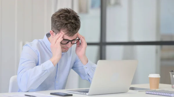 Frustrerad ung man med huvudvärk på jobbet — Stockfoto