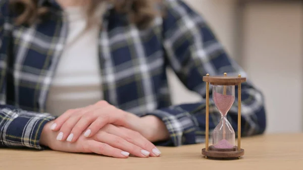 Sablier à côté des mains féminines geste d'attente, Gros plan — Photo