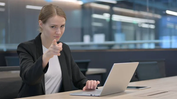 Affärskvinna med bärbar dator pekar mot kameran — Stockfoto