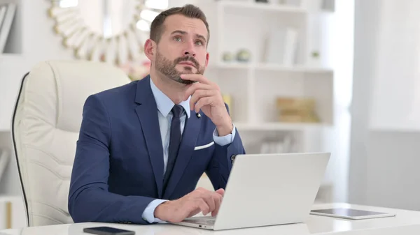 Homme d'affaires Penser et travailler sur ordinateur portable dans le bureau — Photo