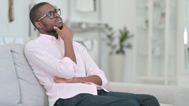 Düşünceli Afrikalı Genç Adam Koltukta oturuyor ve düşünüyor 