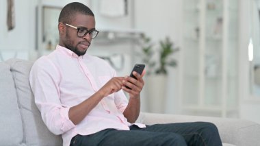 Evde akıllı telefon kullanan rahat bir Afrikalı. 