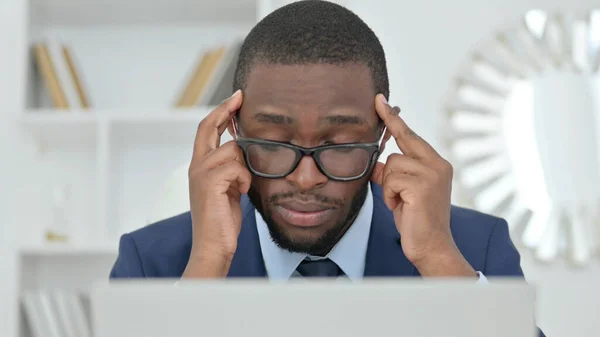 Retrato de un empresario africano con un portátil con dolor de cabeza —  Fotos de Stock