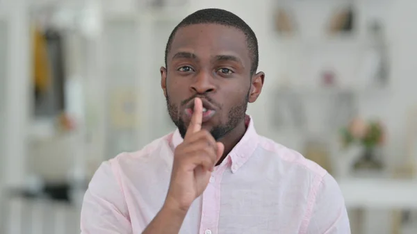 Retrato del hombre africano poniendo dedo en los labios, signo silencioso —  Fotos de Stock