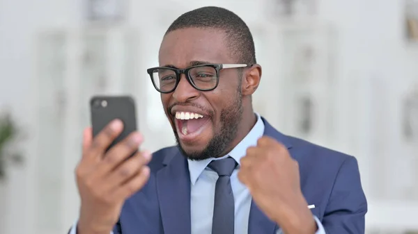 Retrato del empresario africano celebrando el éxito en Smartphone —  Fotos de Stock