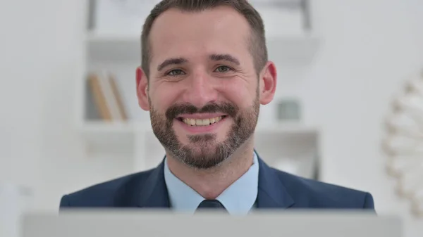 Portret van een aantrekkelijke zakenman met laptop glimlachend naar de camera — Stockfoto