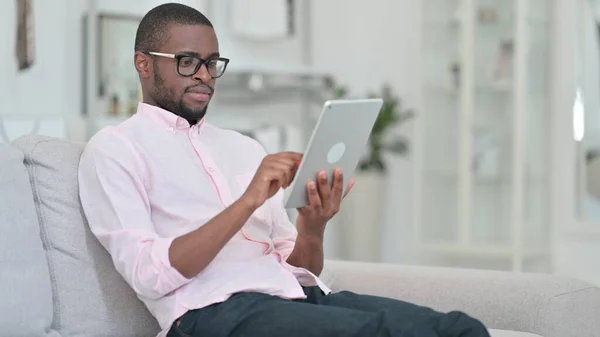 Hombre africano relajado usando tableta digital en casa —  Fotos de Stock