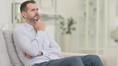 Düşünceli genç adam evde oturuyor ve düşünüyor. 