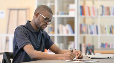 Genç Afrikalı Adam Kütüphanede Düşünüyor ve Evrak Çalışıyor