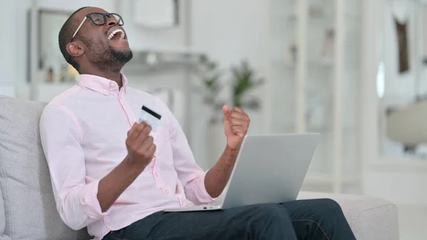 Afrikansk man gör framgångsrika online-betalning på laptop hemma — Stockfoto
