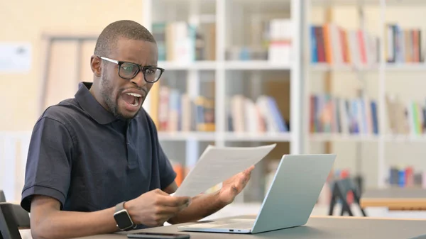 Afrikansk man med förlust arbetar på laptop med dokument — Stockfoto