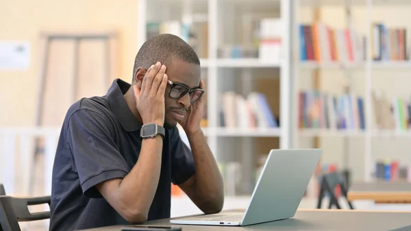 Afrikaanse Man reageert op verlies op laptop in de bibliotheek — Stockfoto